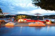 Evening view of the illuminated pool at Alta Insolito Boutique Hotel in Buzios, with scenic ocean and sunset backdrop. 