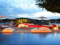 Evening view of the illuminated pool at Alta Insolito Boutique Hotel in Buzios, with scenic ocean and sunset backdrop. 