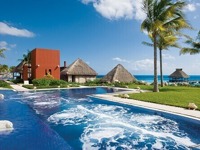 Infinity pool at Zoetry Paraiso de la Bonita Resort in Yucatan, Mexico, with ocean views and palm-lined beachfront. 