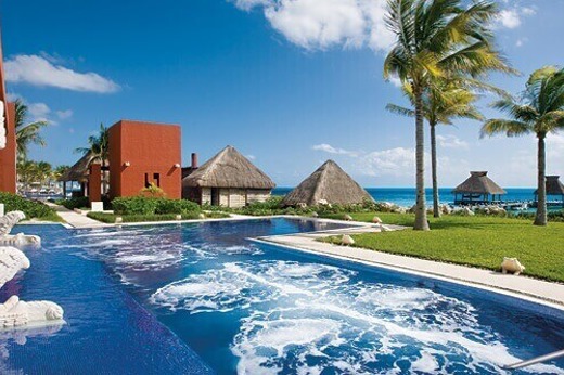 Infinity pool at Zoetry Paraiso de la Bonita Resort in Yucatan, Mexico, with ocean views and palm-lined beachfront. 