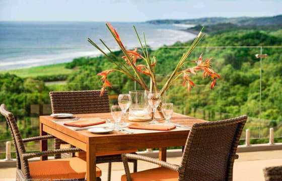 An elegant outdoor table set for two overlooks the lush coastline and Pacific Ocean at Lagarta Lodge. 