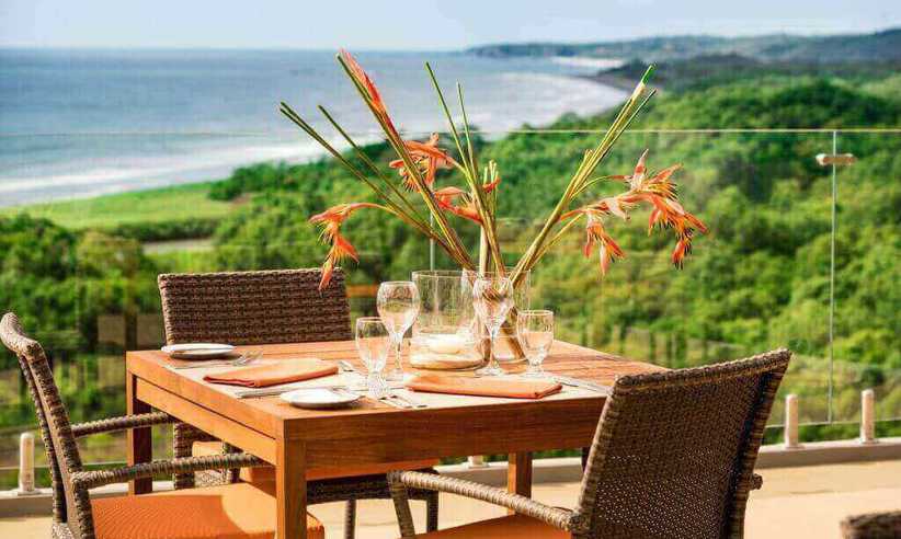 An elegant outdoor table set for two overlooks the lush coastline and Pacific Ocean at Lagarta Lodge. 