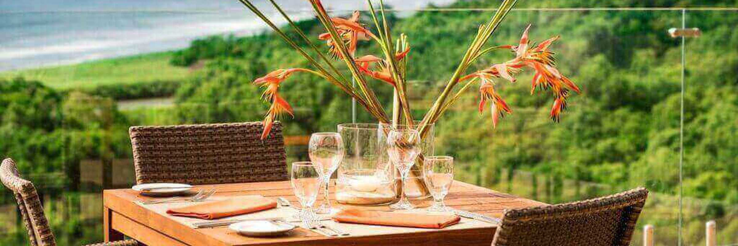 An elegant outdoor table set for two overlooks the lush coastline and Pacific Ocean at Lagarta Lodge. 