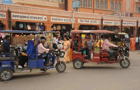 India - Colourful tuk tuks and rickshaws navigate a lively street near the market in Jaipur. 