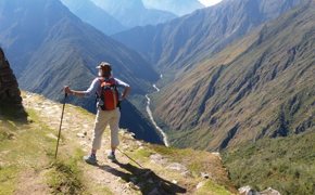 A hiker stands triumphantly atop the Andes, overlooking the Sacred Valley's endless ridges. 