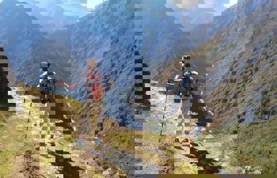 A hiker stands triumphantly atop the Andes, overlooking the Sacred Valley's endless ridges. 
