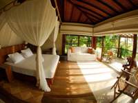 Luxury bungalow suite with canopy bed and garden views at Txai Resort, Ilheus, Bahia, Brazil. 