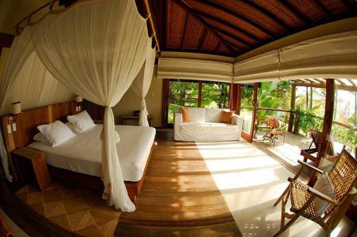 Luxury bungalow suite with canopy bed and garden views at Txai Resort, Ilheus, Bahia, Brazil. 