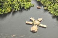 Aerial view of a floating jungle lodge on the Amazon River, surrounded by lush rainforest near Manaus, Brazil. 