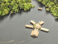 Aerial view of a floating jungle lodge on the Amazon River, surrounded by lush rainforest near Manaus, Brazil. 