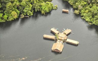 Aerial view of a floating jungle lodge on the Amazon River, surrounded by lush rainforest near Manaus, Brazil. 