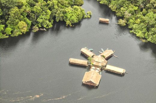 Aerial view of a floating jungle lodge on the Amazon River, surrounded by lush rainforest near Manaus, Brazil. 