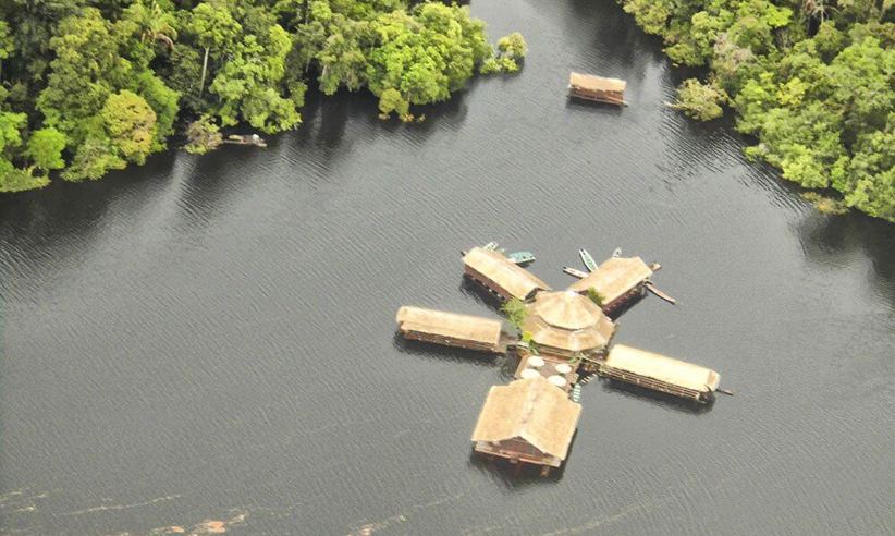 Aerial view of a floating jungle lodge on the Amazon River, surrounded by lush rainforest near Manaus, Brazil. 