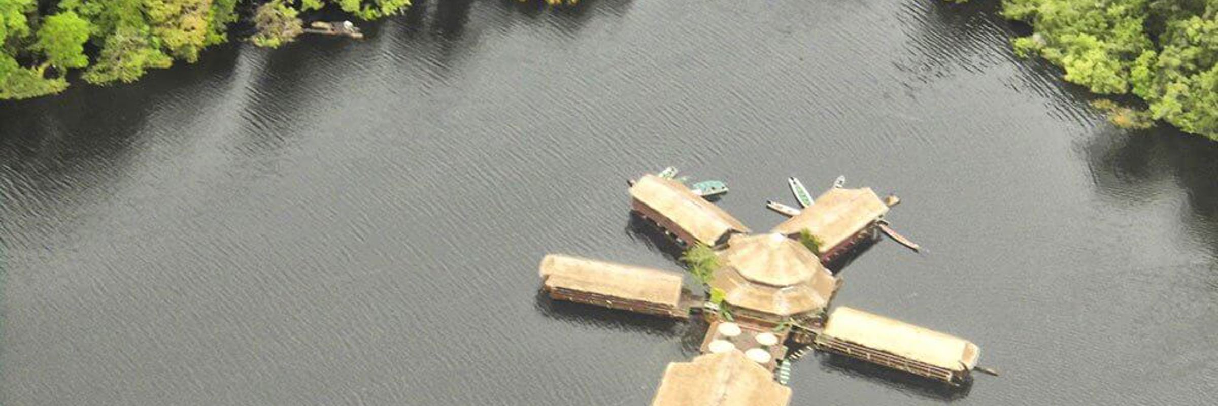 Aerial view of a floating jungle lodge on the Amazon River, surrounded by lush rainforest near Manaus, Brazil. 