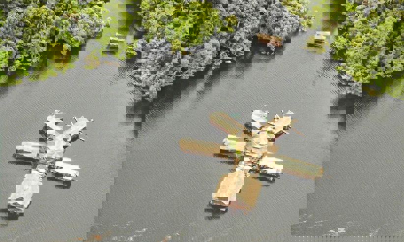 Aerial view of a floating jungle lodge on the Amazon River, surrounded by lush rainforest near Manaus, Brazil. 