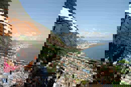 Tourists enjoying drinks with panoramic views over Rio de Janeiro and the favelas from a veranda cafe. 