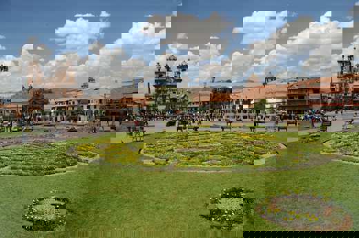 Plaza de Armas in Cusco with manicured gardens and the historic cathedral under blue skies. 