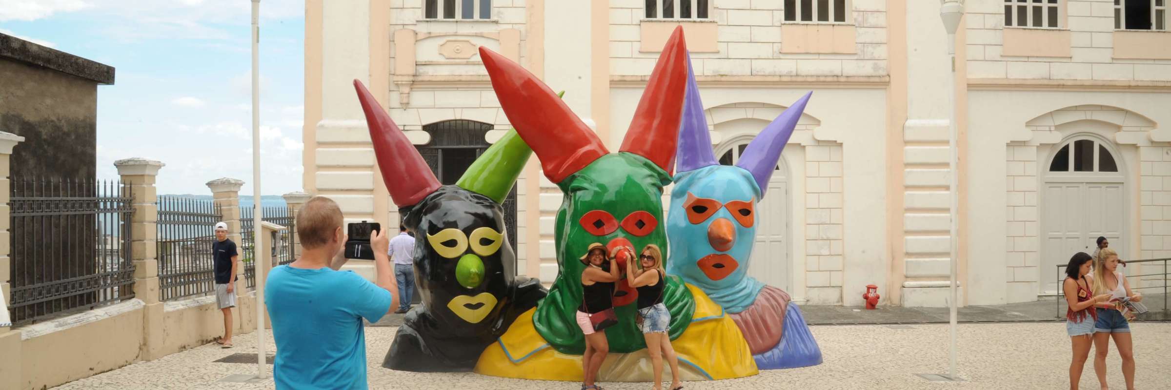 Tourists posing with colourful giant carnival head sculptures in Salvador da Bahia, Brazil. 