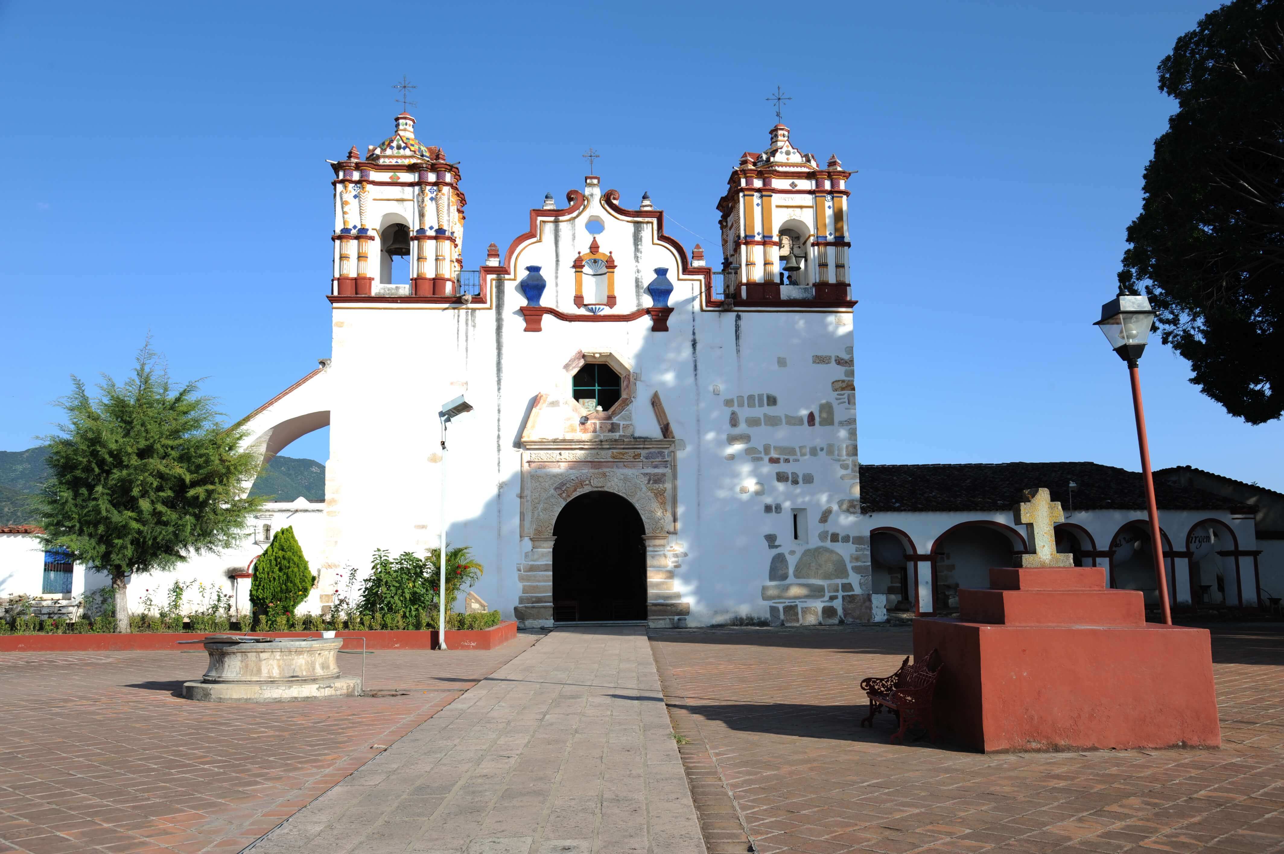 Colorful historic church facade with twin bell towers and courtyard in San Miguel de Allende, Mexico. 