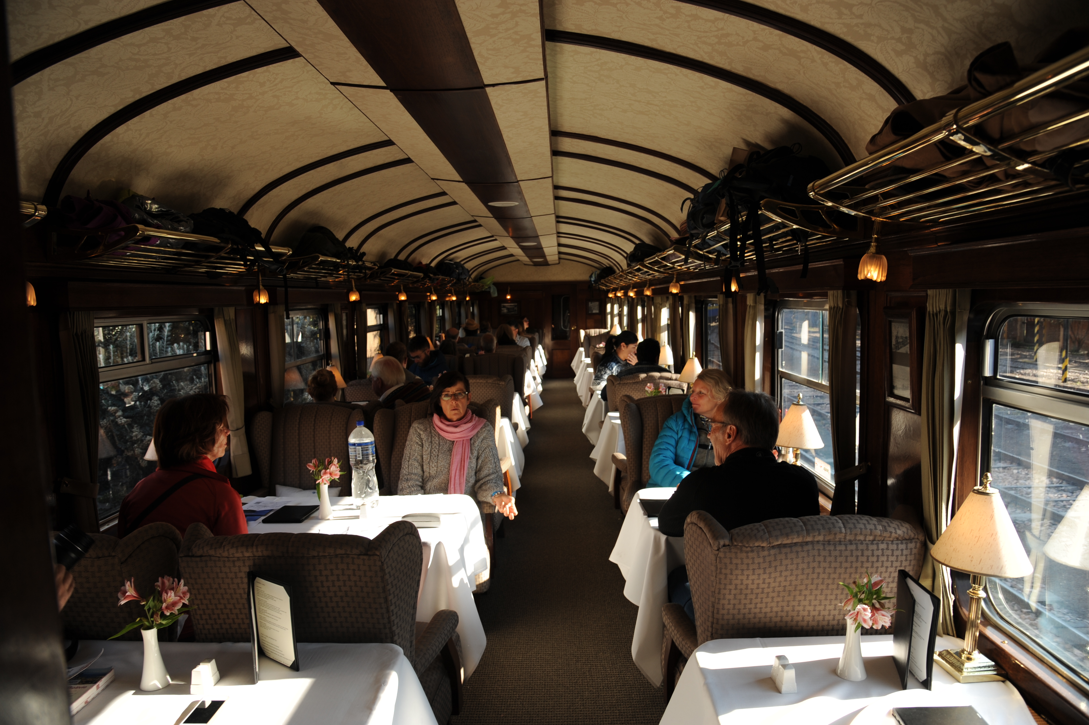 Guests enjoying fine dining inside the Belmond Andean Explorer's elegant carriage as it journeys through the Peruvian Andes. 