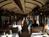 Guests enjoying fine dining inside the Belmond Andean Explorer's elegant carriage as it journeys through the Peruvian Andes. 
