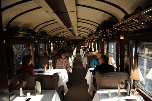Guests enjoying fine dining inside the Belmond Andean Explorer's elegant carriage as it journeys through the Peruvian Andes. 