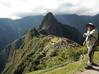 Guide standing above Machu Picchu with panoramic views of the Inca ruins and Andes Mountains. 