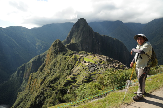 Guide standing above Machu Picchu with panoramic views of the Inca ruins and Andes Mountains. 