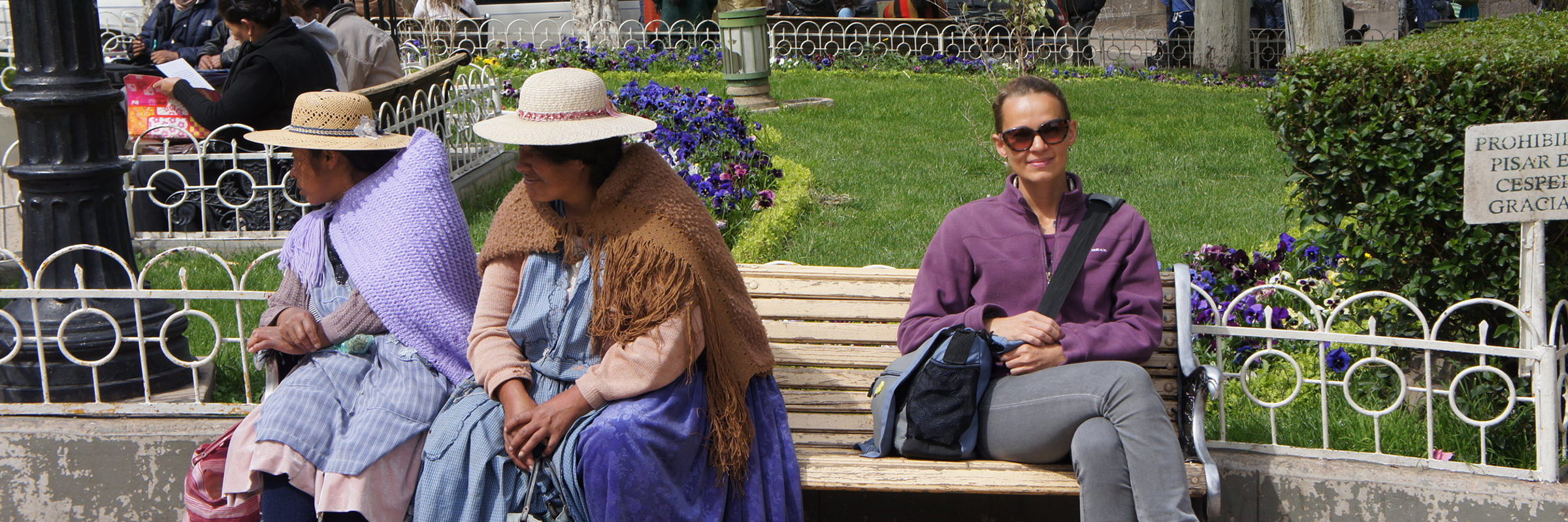 Locals relax on park benches in Bolivia, blending traditional and modern styles. 