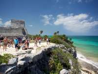 Visitors explore the cliffside Mayan ruins of Tulum overlooking the turquoise Caribbean Sea in Mexico's Yucatan Peninsula. 