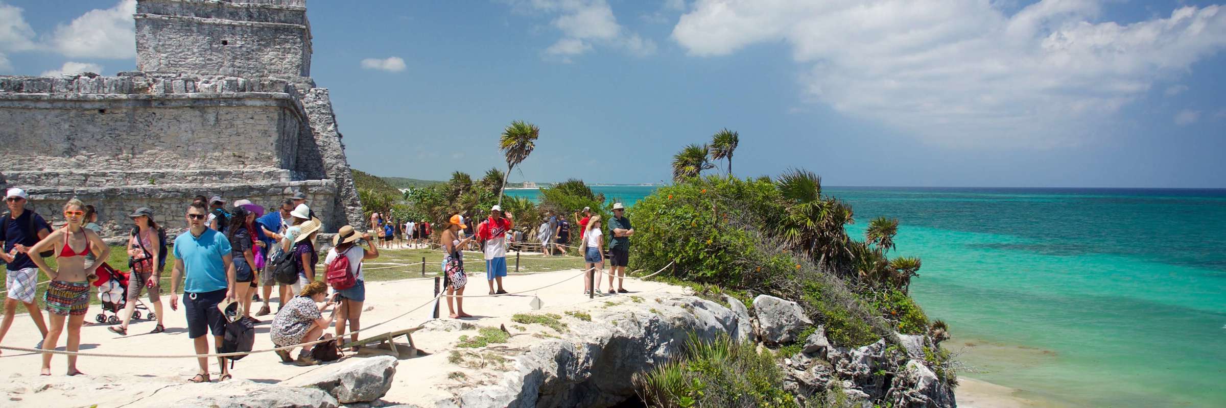 Visitors explore the cliffside Mayan ruins of Tulum overlooking the turquoise Caribbean Sea in Mexico's Yucatan Peninsula. 