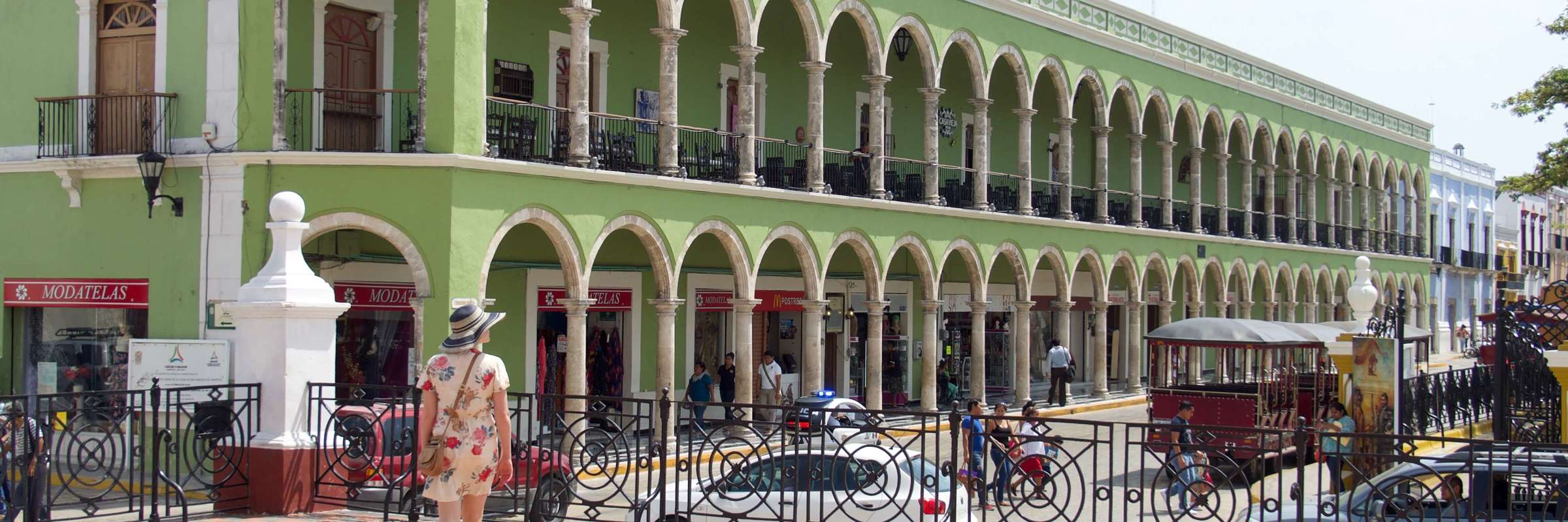 Historic green arcade building on Merida's Plaza Grande, Yucatan, with colonial arches, statue, and pedestrian view. 
