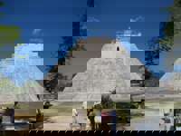 The Pyramid of the Magician at Uxmal, Yucatan, Mexico, a towering Mayan structure with steep sides and tourists at the base. 