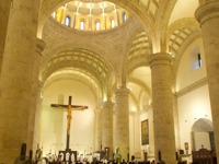 Interior of the Cathedral of Merida, Yucatan, with worshipers gathered beneath soaring arches and a large crucifix. 