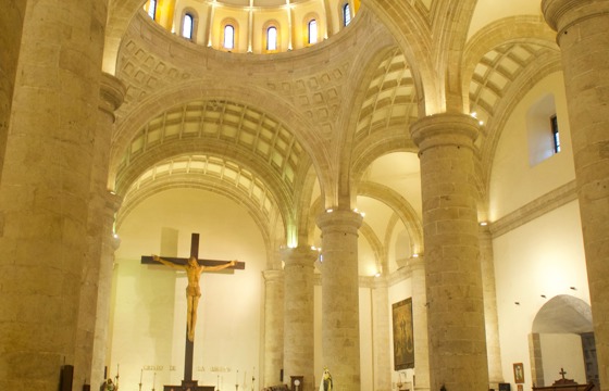 Interior of the Cathedral of Merida, Yucatan, with worshipers gathered beneath soaring arches and a large crucifix. 