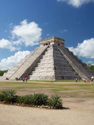 The Temple of Kukulcan at Chichen Itza rises under a bright sky, showcasing ancient Mayan architectural brilliance. 