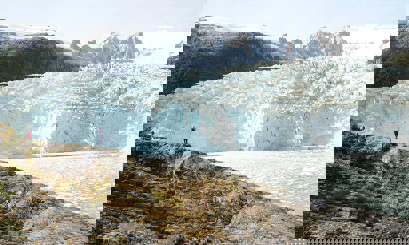 Hikers stand on a rocky outcrop overlooking a massive glacier during an Australis cruise expedition in southern Chile. 
