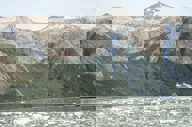 An expedition cruise ship navigates icy Patagonia waters beneath towering, rugged mountains in Chile's southern fjords. 