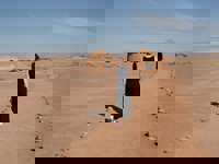 Traditional huts in the Atacama Desert with a lone traveler walking across the sandy landscape under clear skies. 
