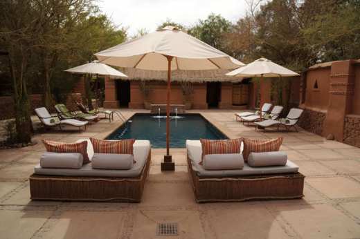 Relaxing poolside loungers and parasols in a stylish desert retreat, perfect for unwinding in Chile's Atacama region. 