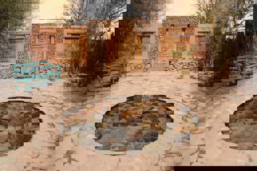 A peaceful stone courtyard in Chile's Atacama Desert features a circular pond, rustic wooden doors, and a turquoise bench. 