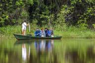 Tourists on a guided canoe through the Peruvian Amazon rainforest, exploring jungle wildlife. 