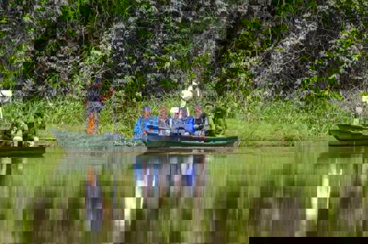Tourists on a guided canoe through the Peruvian Amazon rainforest, exploring jungle wildlife. 