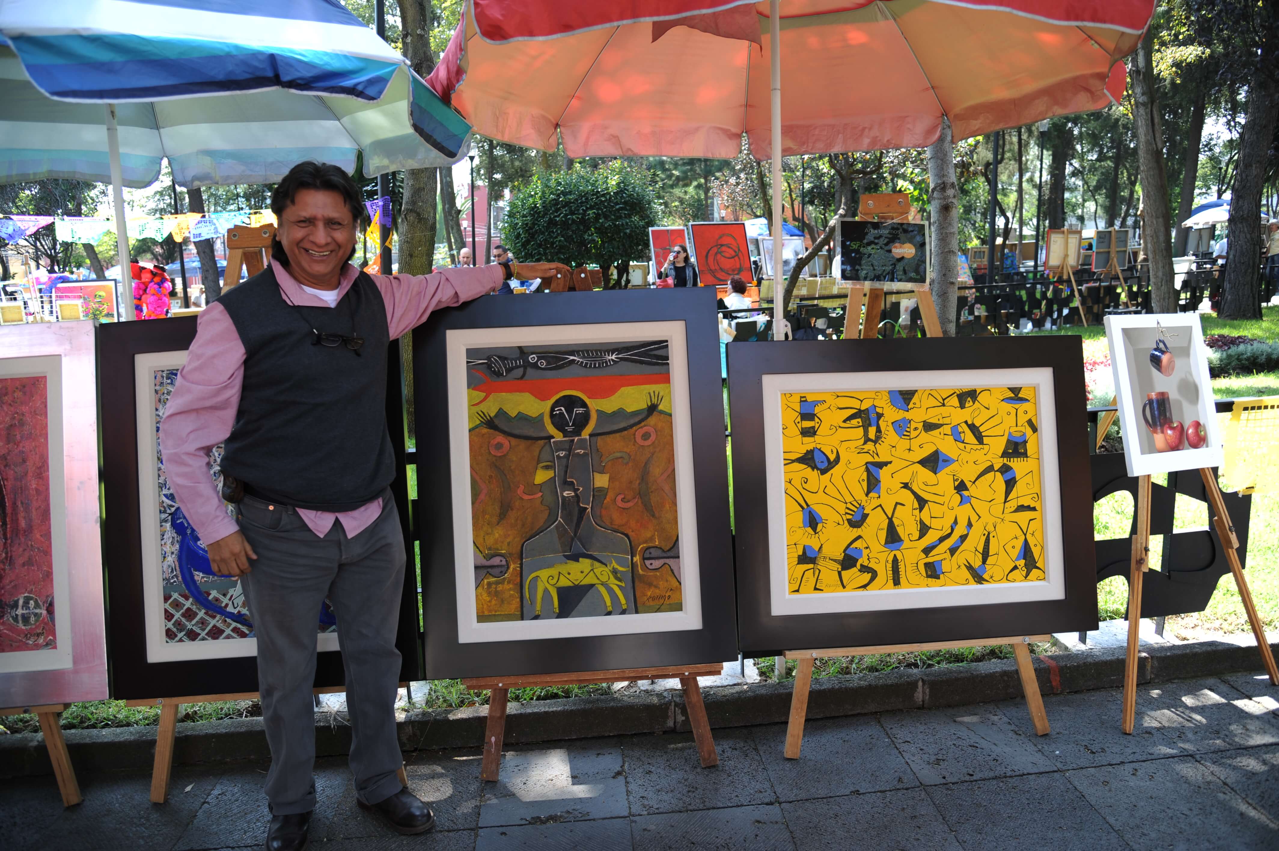 Mexican artists showcasing vibrant handmade paintings at an outdoor market in Mexico City. 
