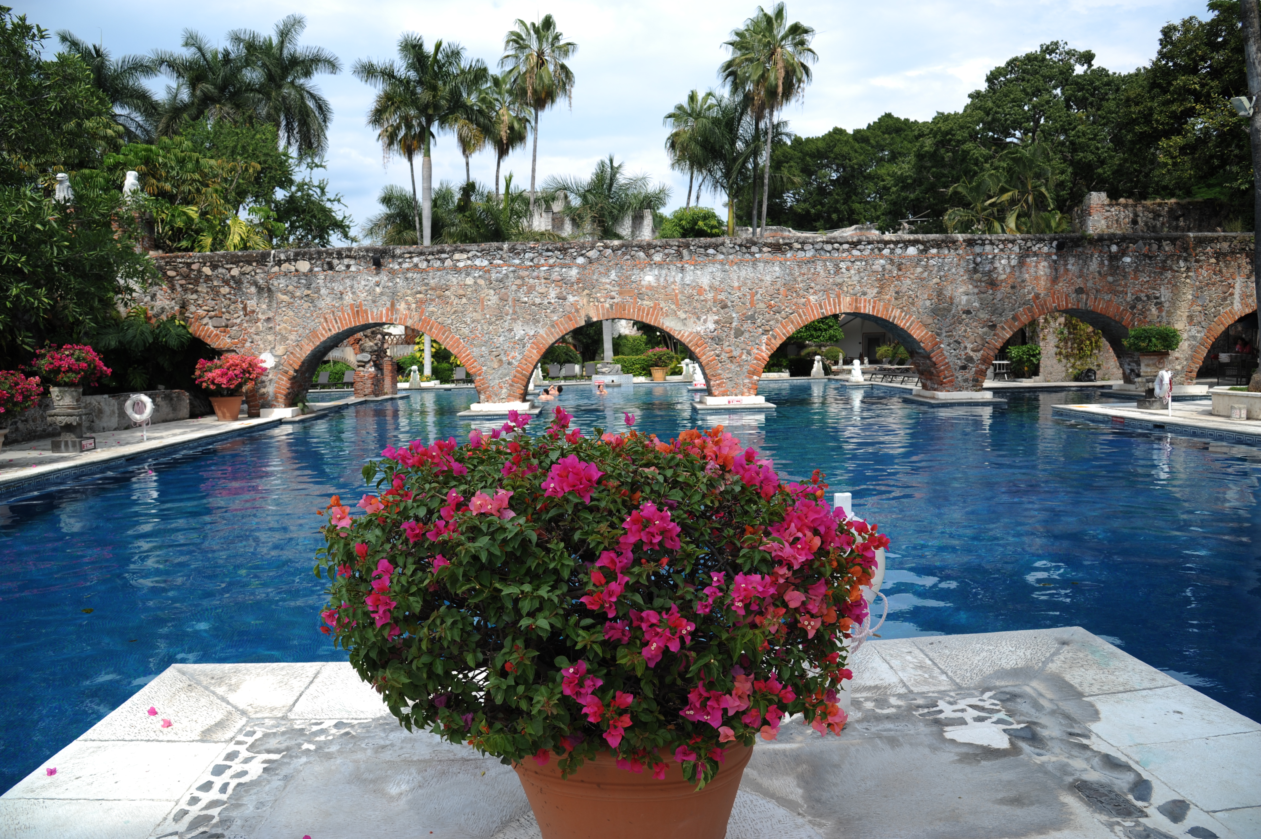Elegant stone arches and tropical gardens surround a serene pool at a historic Mexican hacienda. 