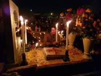 A candlelit Day of the Dead altar in a Mexican cemetery, decorate with flowers, photos and offerings during a nighttime vigil. 