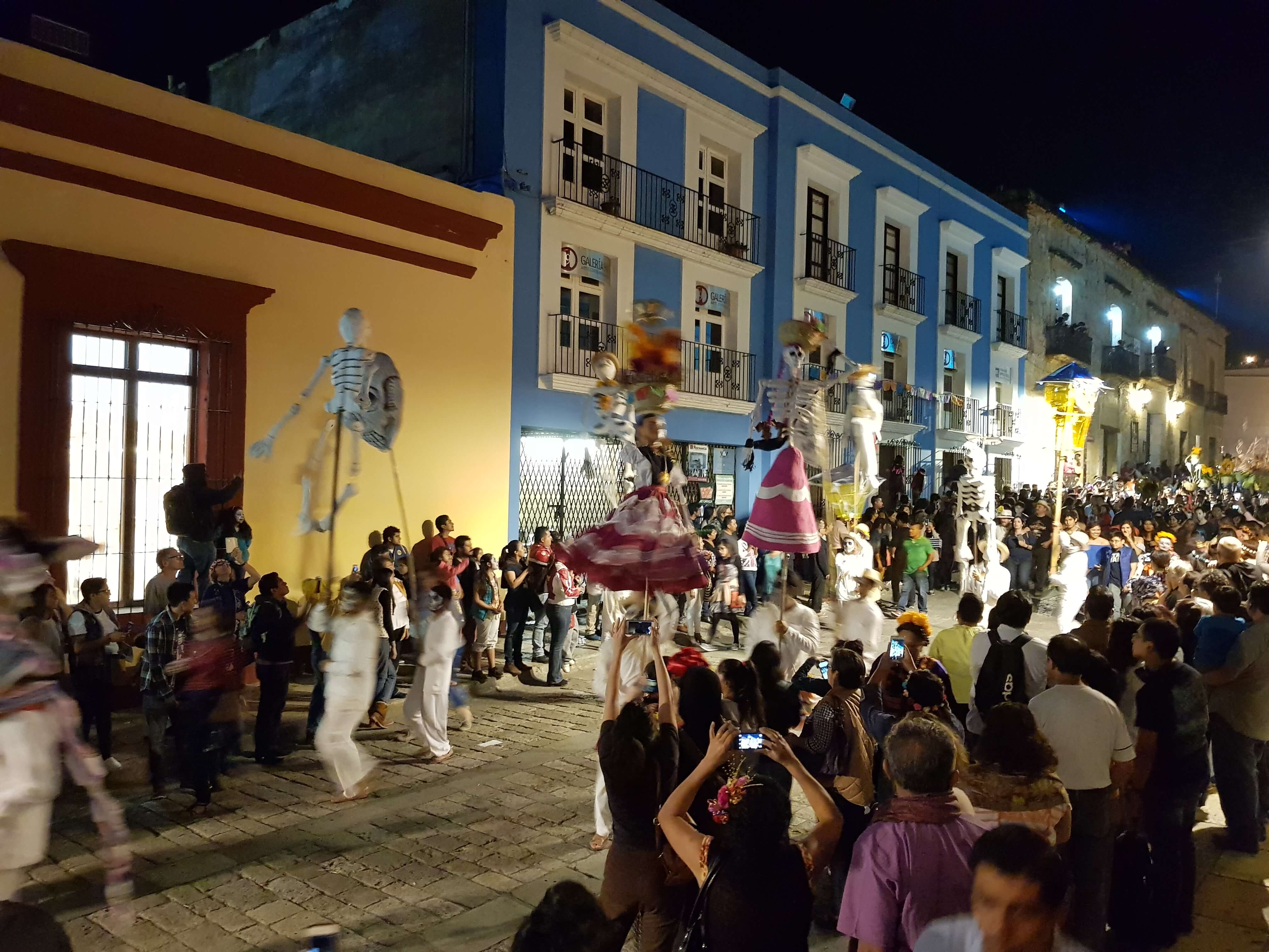Vibrant Day of the Dead parade in Oaxaca, Mexico with giant skeleton puppets, dancers, and colourful street decorations. 