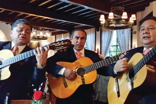 Three traditional Mexican guitarists perform indoors, capturing the spirit and musical heritage of Mexico. 