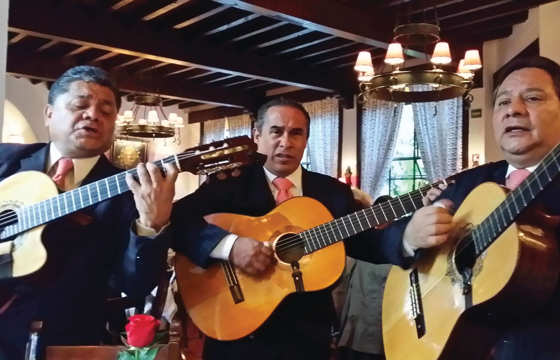 Three traditional Mexican guitarists perform indoors, capturing the spirit and musical heritage of Mexico. 