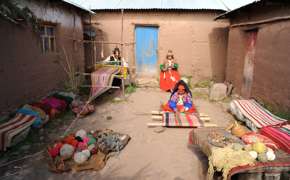 A family gathers in a quiet courtyard, surrounded by woven blankets and rural charm near Lake Titicaca. 